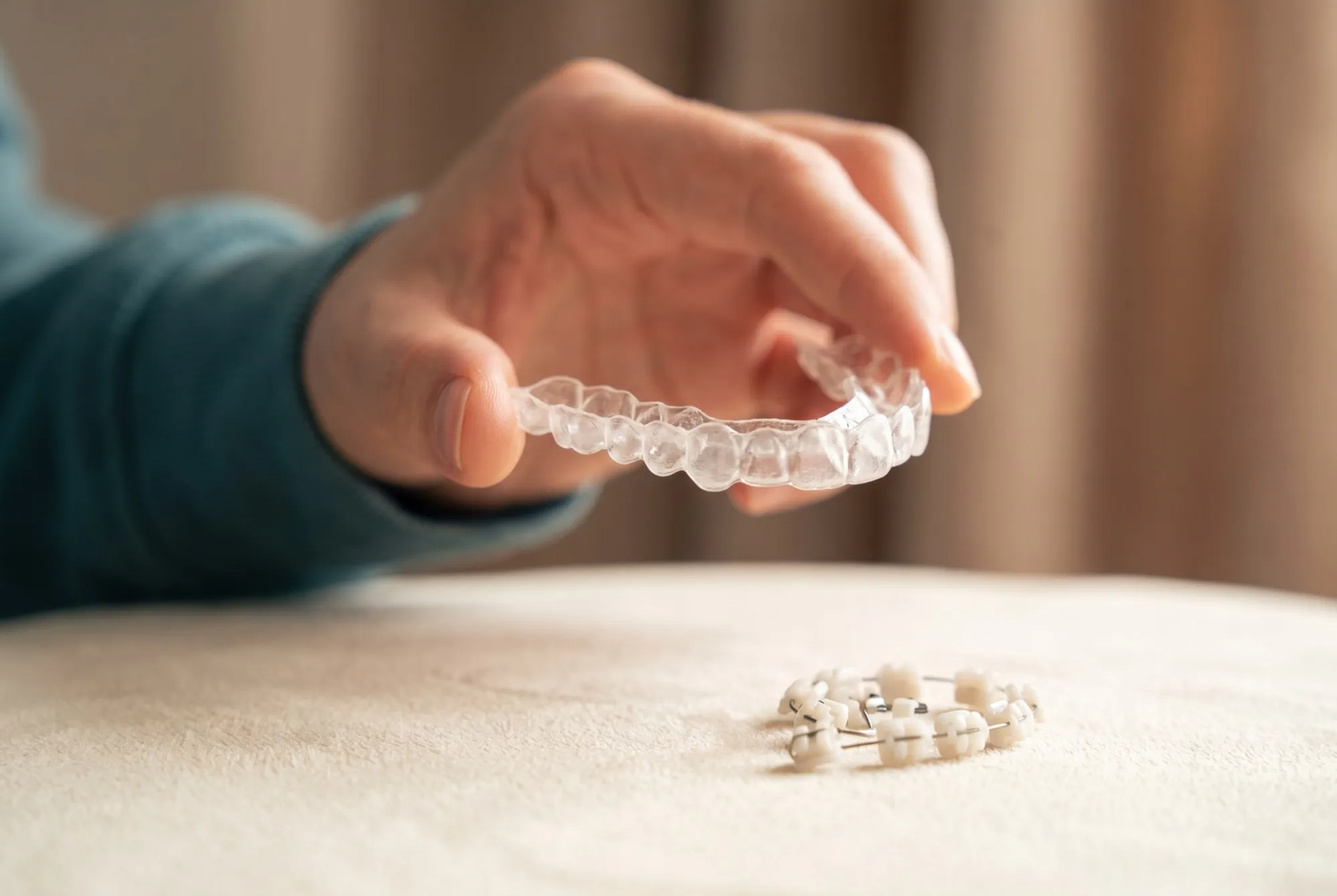 Gutieră transparentă ținută în mână, cu bracket-uri ceramice dedesubt
